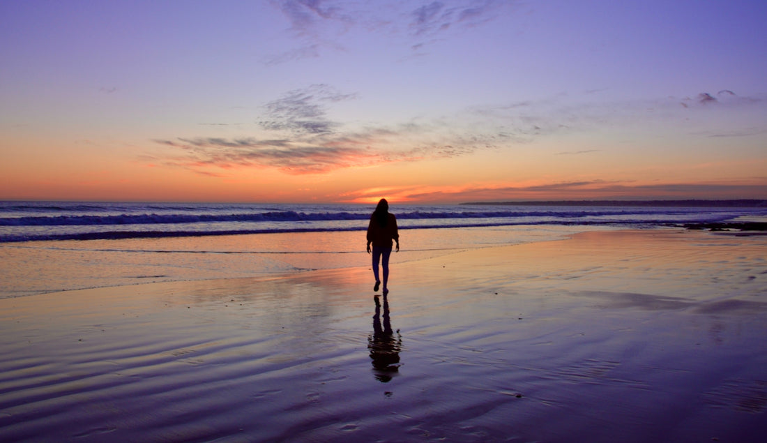 silhouette of person standing on beach during sunset